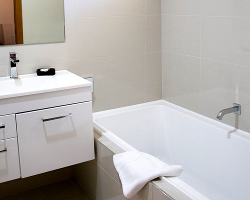 A bathroom with open vanity and bath tub.