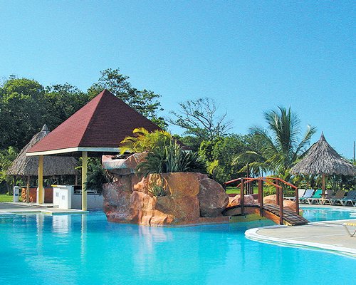 An outdoor swimming pool with thatched sunshades.