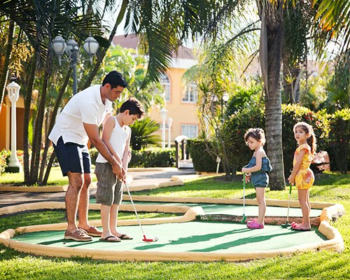 A man playing golf with kids alongside resort units.