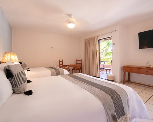 A well furnished bedroom with two beds and a balcony with patio.
