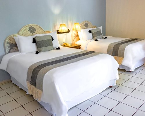 A bedroom with two double beds and a balcony.