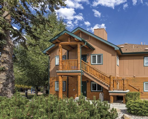 An exterior view of multi story resort units with shrubs and trees.