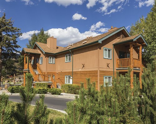 A street view of multi story resort units with shrubs and trees.