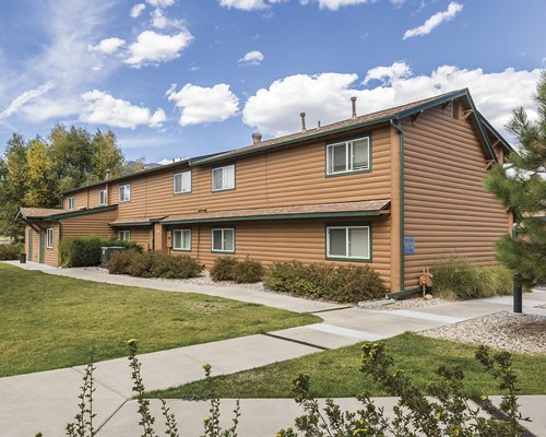 Street view of a resort unit with trees and shrubs.
