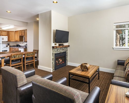 An open plan living dining and kitchen area with a television and fire in the fireplace.