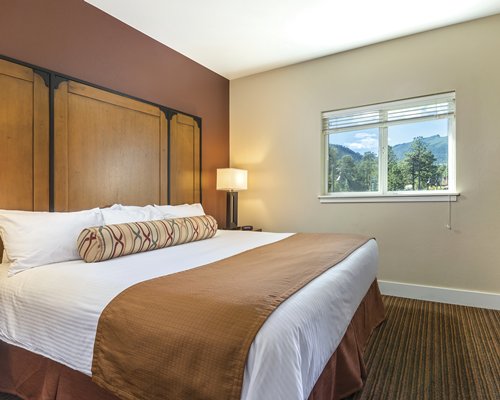 A well furnished bedroom with king bed and outside view.