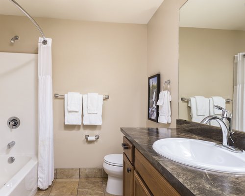 A bathroom with a bathtub and single sink vanity.