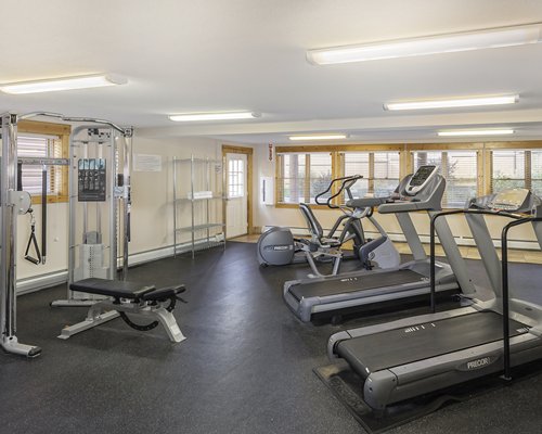 A well equipped indoor fitness center with an outside view.