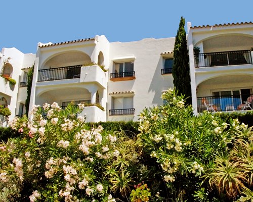 An exterior view of the resort with private balconies and flowering shrubs.