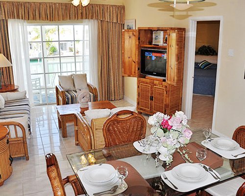 An open plan living and dining area with a television and balcony.