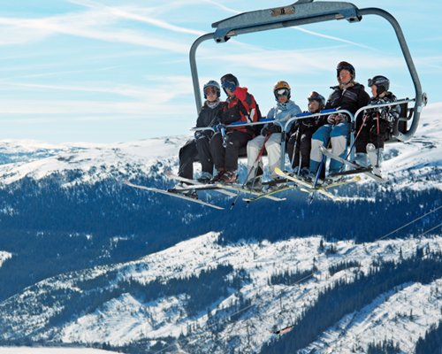 View of people on the chairlift above the wooded area during winter.