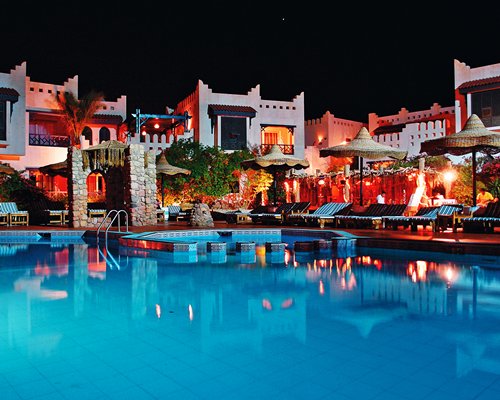 An outdoor swimming pool alongside the resort at night.