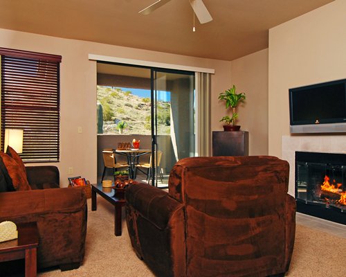 A well furnished living room with a television fire in the fireplace and balcony.