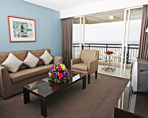A well furnished living room with a television double pull out sofa and a balcony.