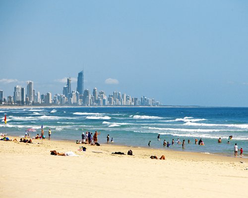 A view of the beach alongside the ocean and skyscrapers.