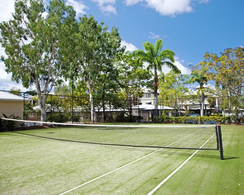 An outdoor tennis court with trees alongside resort units.