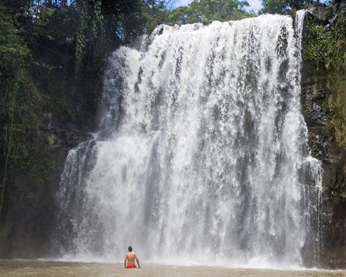 A man standing before the waterfall.