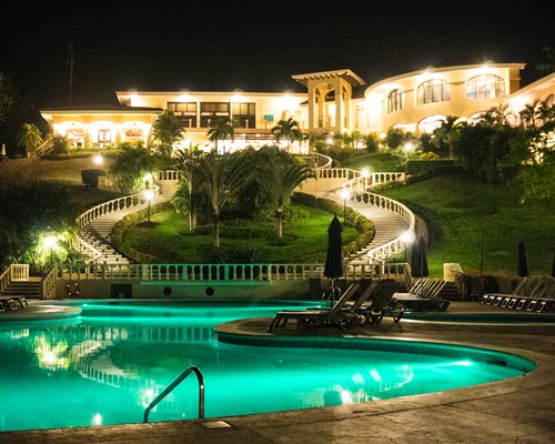 Exterior view of the resort with outdoor swimming pool at night.
