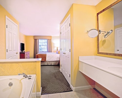 A well furnished bedroom with king bed television shower bathtub and outside view.