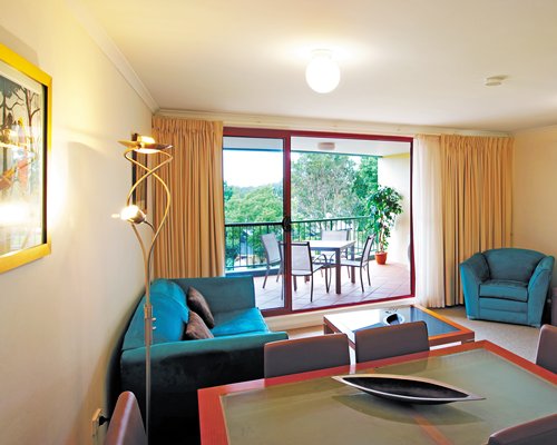 A well furnished living room with patio furniture in the balcony.