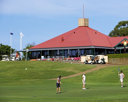 Group of people playing golf in a well maintained golf course alongside the resort.