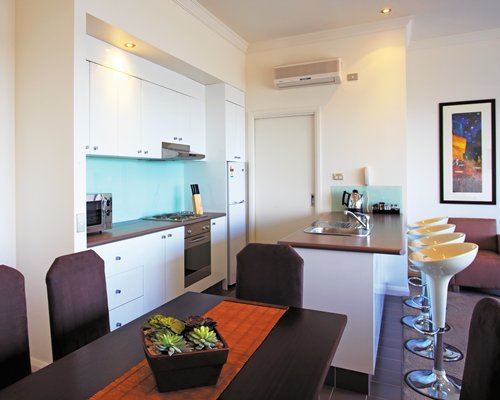 A well furnished dining area alongside the kitchen with a breakfast bar.
