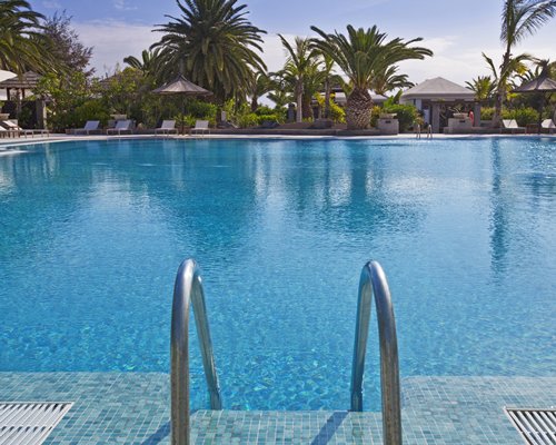An outdoor swimming pool with chaise lounge chairs and sunshades.
