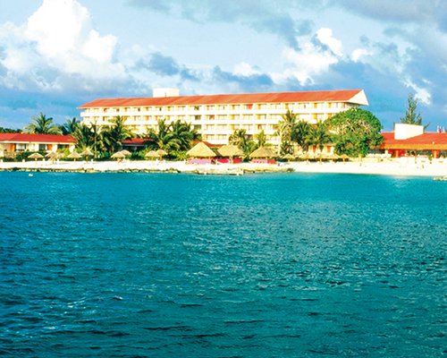 Scenic exterior view of Presidente Intercontinental Cozumel alongside the beach with sunshades.