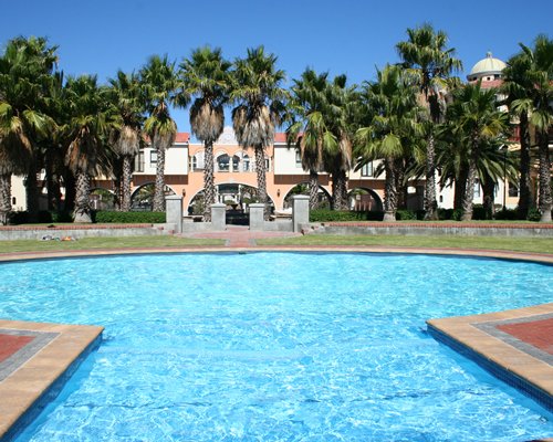 An outdoor swimming pool alongside the resort with palm trees.