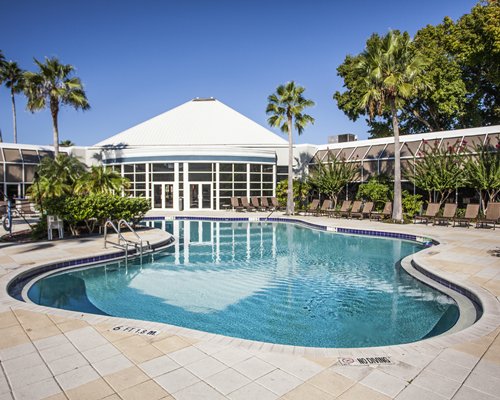 Scenic view of an outdoor swimming pool with chaise lounge chairs alongside the resort.