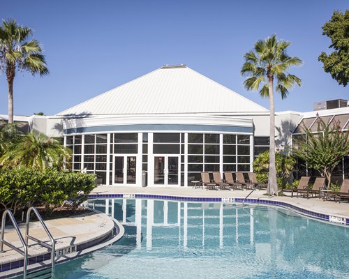 An outdoor swimming pool with chaise lounge chair alongside the resort.