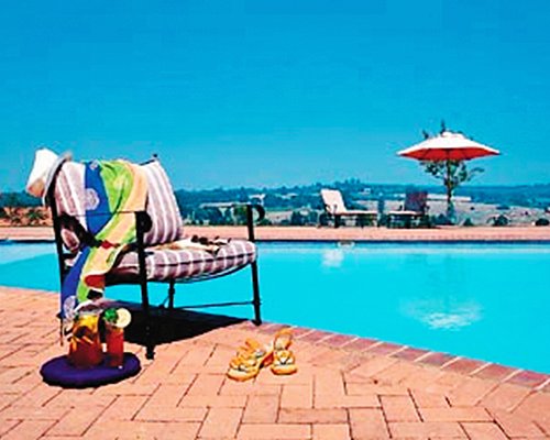 Outdoor swimming pool with patio chair chaise lounge chairs and sunshade.