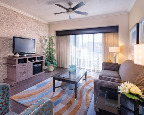 A WELL FURNISHED LIVING ROOM WITH A TELEVISION AND BALCONY.