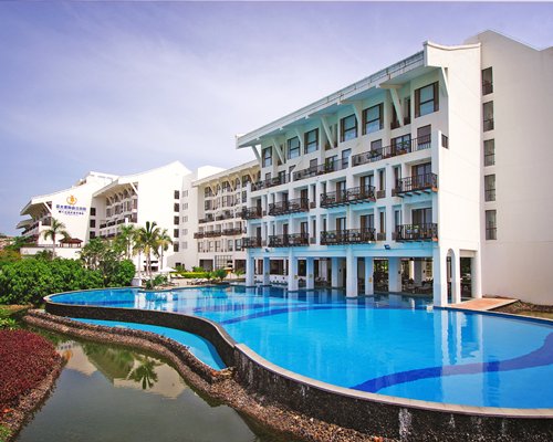 An outdoor swimming pool alongside multi story unit with private balconies.