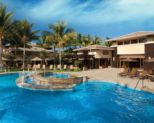 A large outdoor swimming pool with chaise lounge chairs alongside the resort.