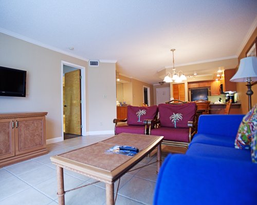 A well furnished living room with a television dining area and open plan kitchen.
