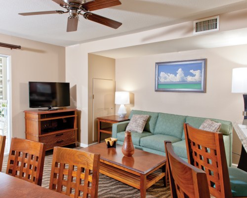 An open plan living room with a television sofa and wooden dining table.