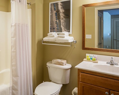 A bathroom with a bathtub shower and single sink vanity.