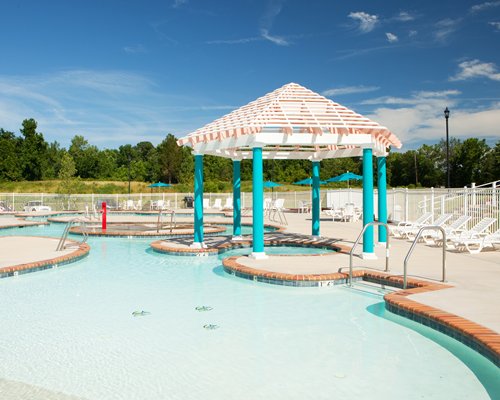 Outdoor swimming pool with gazebo and chaise lounge chairs.