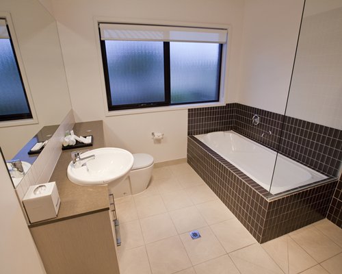 A bathroom with a sink a toilet vanity and a bathtub.