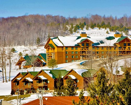 An exterior view of multi story resort units and trees covered in snow.