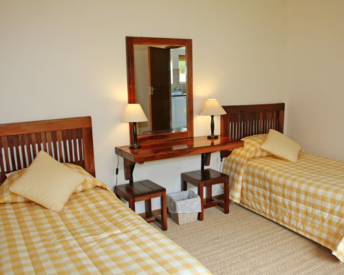 A well furnished bedroom with two beds and mirror.