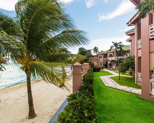 Scenic exterior view of Grand Colony Island Villas alongside the beach with palm trees.