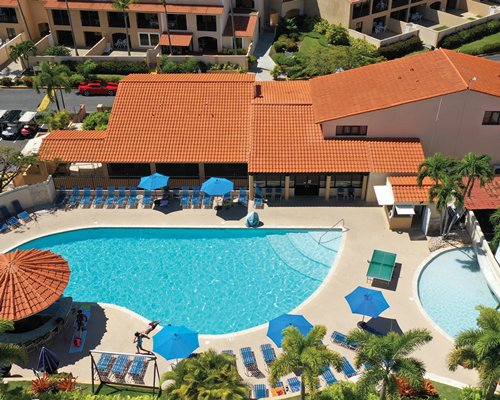 Outdoor swimming pool with chaise lounge sofa sunshade and beach bed surrounded by wooded area.