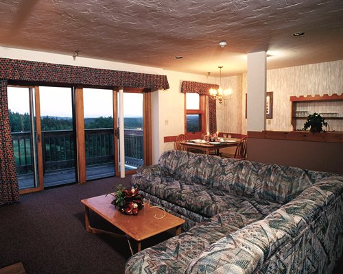 An open plan living room with a sofa dining table and outside view.