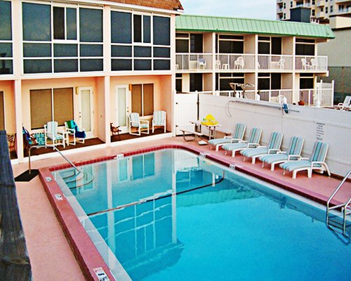 View of multiple balconies with outdoor swimming pool patio chairs and chaise lounge chairs.