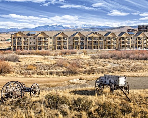 Exterior view of Worldmark Granby Rocky Mountain Preserve with a wooden cart surrounded by wooded area.