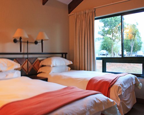 A well furnished bedroom with two twin beds and an outside view.