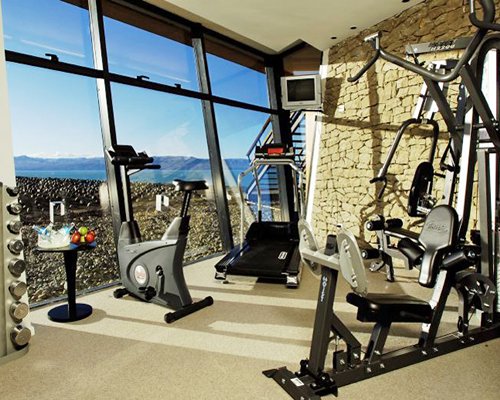 A well equipped indoor fitness center with television.