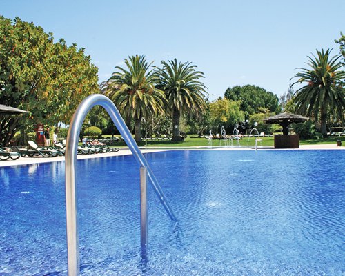 A large outdoor swimming pool with chaise lounge chairs and trees.